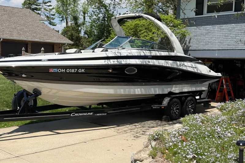 Slide: The Image of 2022 Crownline 280 SS boat on trailer in driveway, surrounded by greenery. - 4