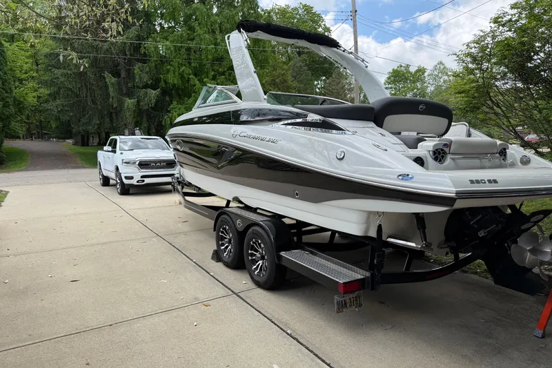 Slide: The Image of 2022 Crownline 280 SS boat on trailer, parked in driveway with a white truck. - 5