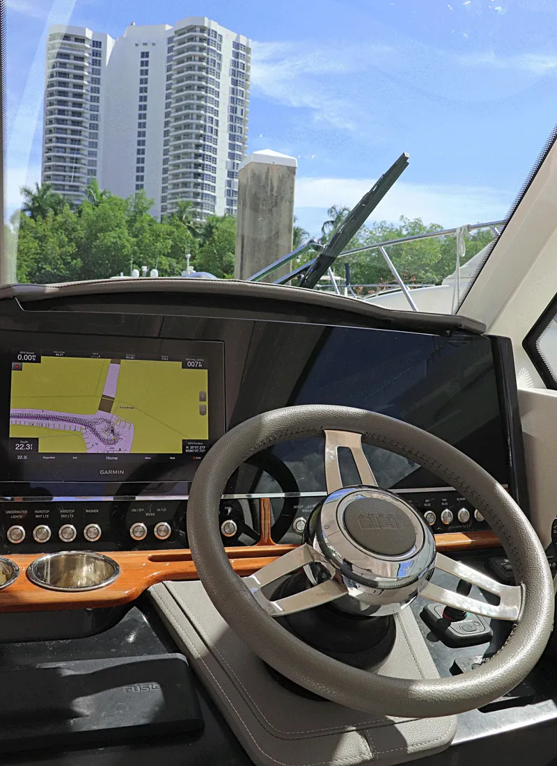Slide: The Image of 2021 Tiara Sport 34 LX helm with navigation display, steering wheel, and cityscape view. - 14