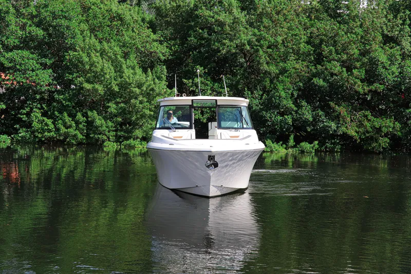 Slide: The Image of 2021 Tiara Sport 34 LX boat cruising on a calm, tree-lined waterway. - 3