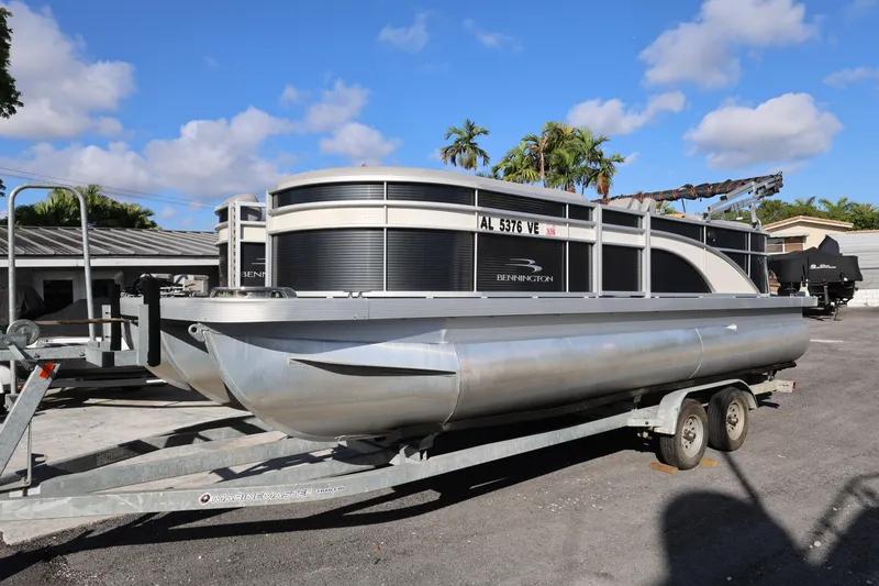 The Image of 2020 Bennington SX 22 SSRX pontoon boat on trailer, parked outdoors under blue sky. - 0