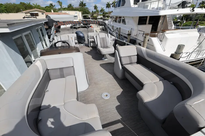 Slide: The Image of 2020 Bennington SX 22 SSRX pontoon boat with spacious seating, docked near luxury yachts. - 12