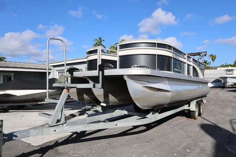 Slide: The Image of 2020 Bennington SX 22 SSRX pontoon boat on trailer under clear blue sky. - 2