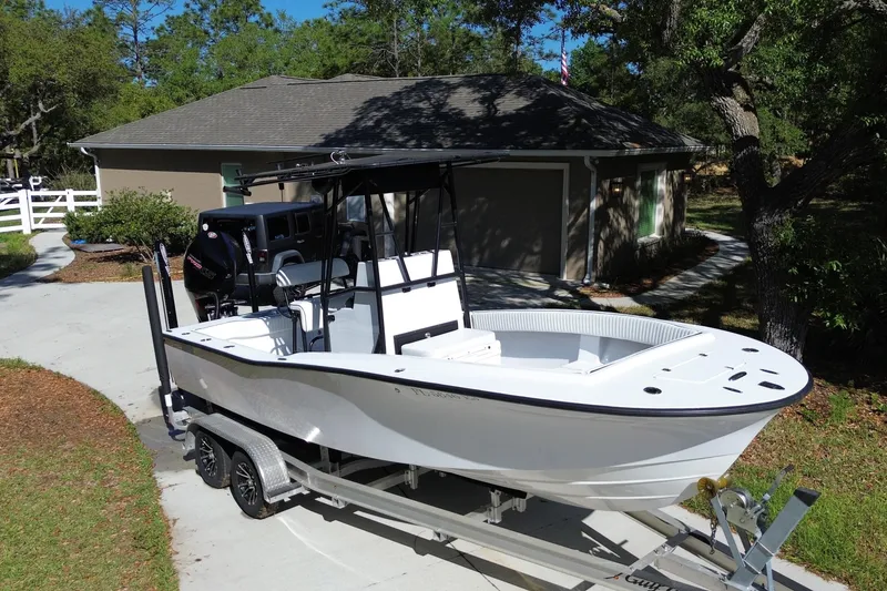 The Image of 1984 Chris-Craft 213 Scorpion boat on trailer in driveway, surrounded by trees. - 0