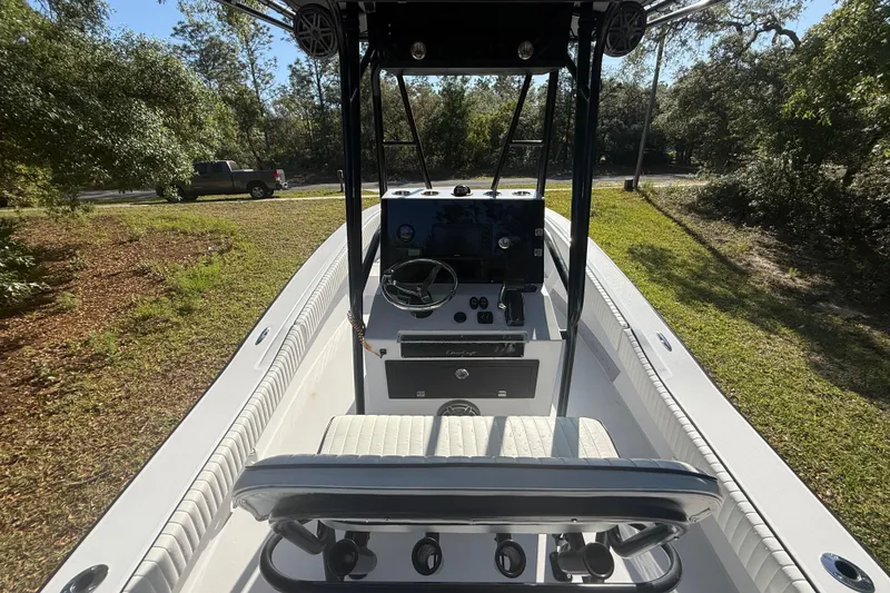 Slide: The Image of 1984 Chris-Craft 213 Scorpion boat interior with steering console and seating, surrounded by greenery. - 19