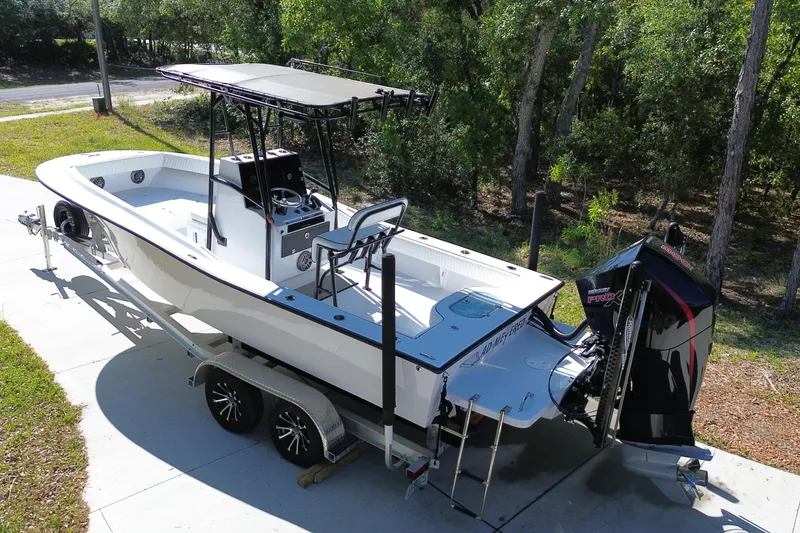 Slide: The Image of 1984 Chris-Craft 213 Scorpion boat on trailer, surrounded by trees, featuring a powerful outboard motor. - 4