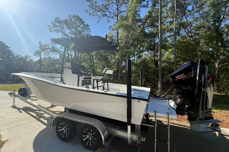 Slide: The Image of 1984 Chris-Craft 213 Scorpion boat on trailer, surrounded by trees, under clear blue sky. - 8