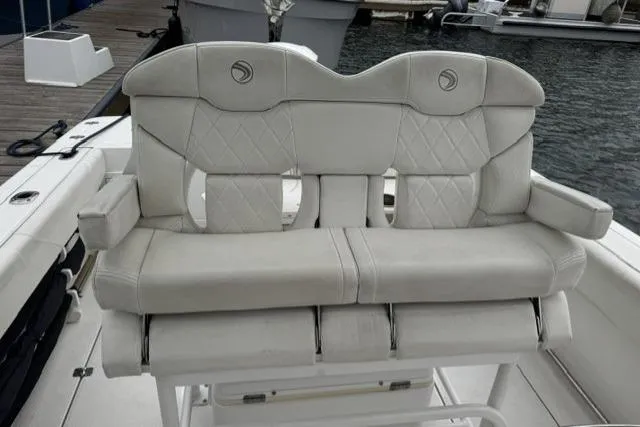 Slide: The Image of Edgewater 245CC 2019 boat seat with quilted design, docked by the water. - 12