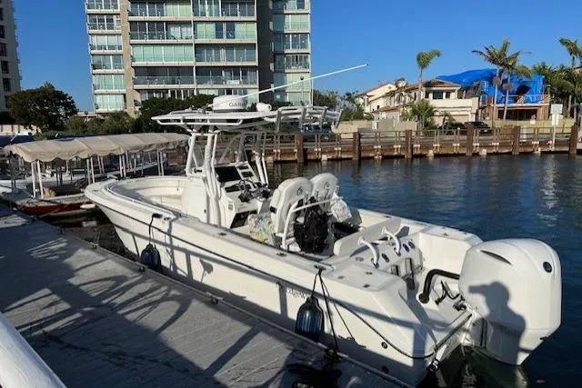 Slide: The Image of 2019 Edgewater 245CC boat docked by waterfront buildings and palm trees. - 5