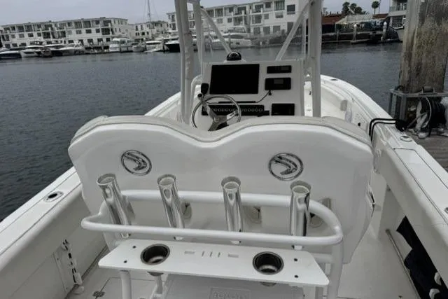 Slide: The Image of 2019 Edgewater 245CC boat interior with rod holders, docked in a marina. - 6