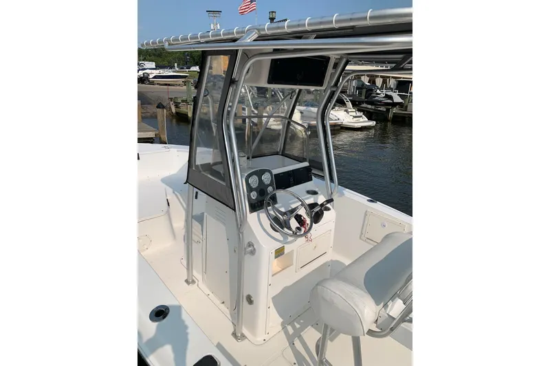 Slide: The Image of 2006 Sea Hunt Triton 220 boat cockpit with steering wheel and controls, docked near water. - 13