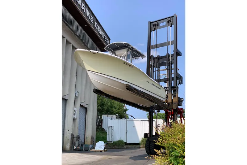 Slide: The Image of 2006 Sea Hunt Triton 220 boat lifted by forklift at marine center. - 3
