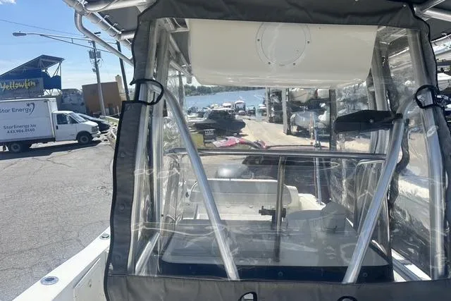 Slide: The Image of 2006 Sea Hunt Triton 220 boat with clear enclosure, docked near waterfront. - 33