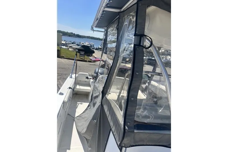 Slide: The Image of 2006 Sea Hunt Triton 220 boat with clear canopy, docked near a scenic waterfront. - 34