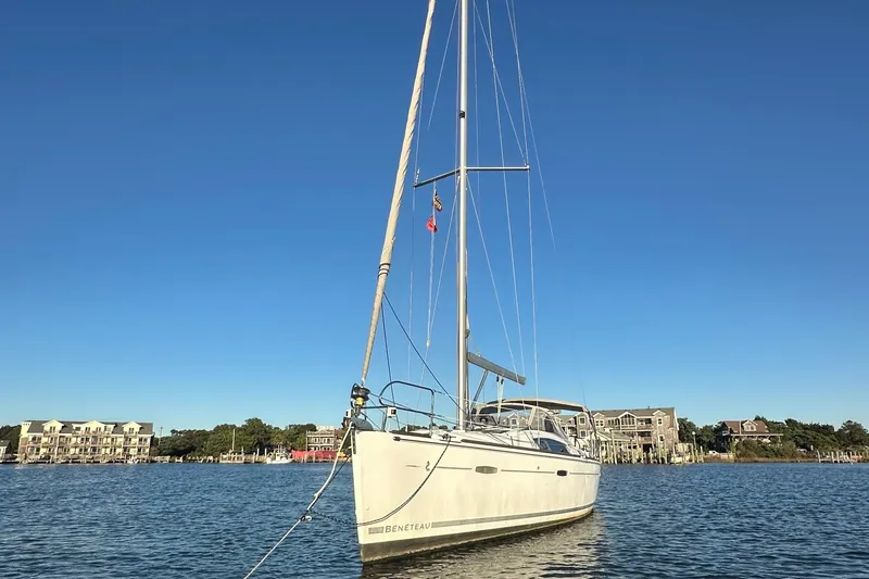 Slide: The Image of 2009 Beneteau Oceanis 40 sailboat anchored in a scenic harbor under clear blue skies. - 2