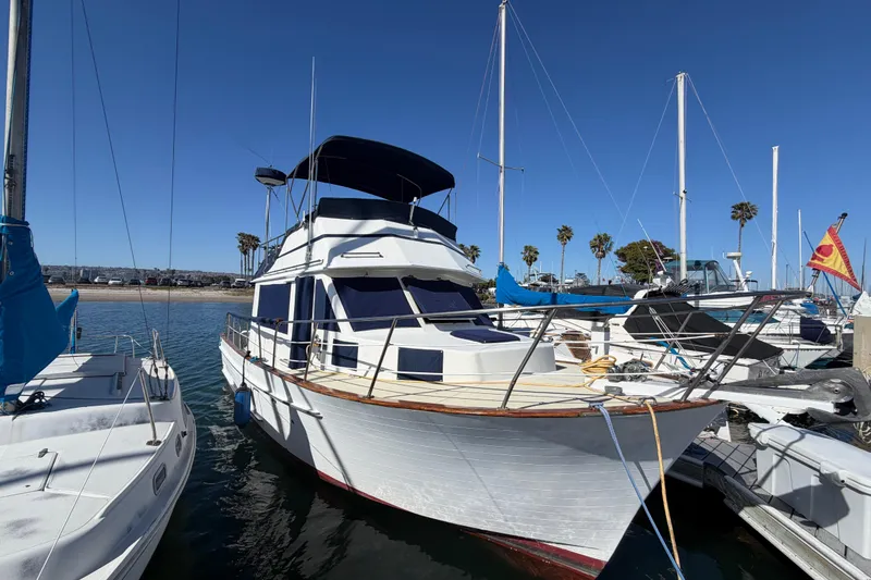 Slide: The Image of 1982 Lien Hwa 31 yacht docked at marina, clear blue sky, palm trees in background. - 74
