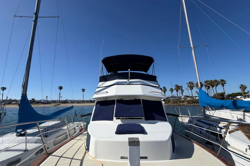 Slide: The Image of 1982 Lien Hwa 31 yacht docked, surrounded by sailboats, with clear blue sky and palm trees. - 75