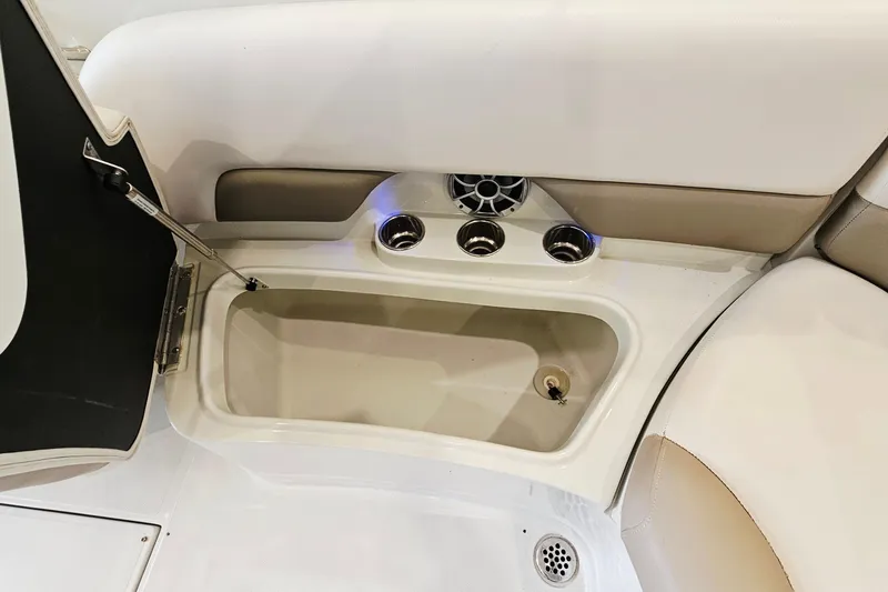Slide: The Image of 2014 Crownline 255 SS boat interior with open storage compartment and cup holders. - 25