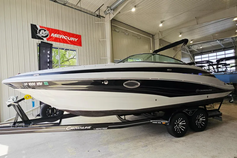 Slide: The Image of 2014 Crownline 255 SS boat on trailer in indoor showroom with Mercury banner. - 3
