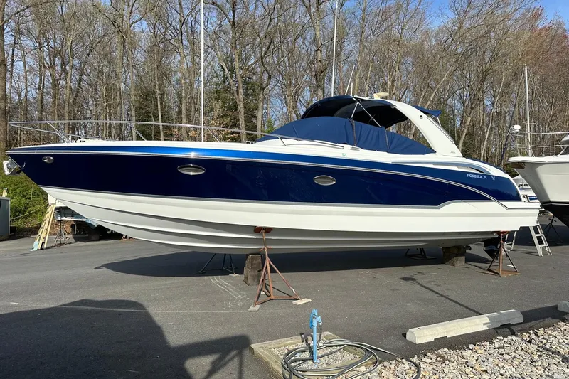 The Image of 2009 Formula 350 Sun Sport boat on stands, blue and white design, parked outdoors. - 0