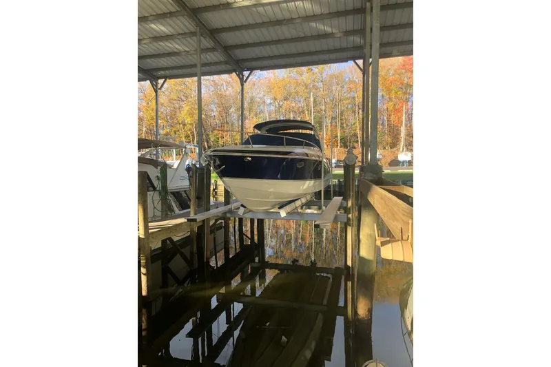 Slide: The Image of 2009 Formula 350 Sun Sport boat docked under a covered marina with autumn trees in the background. - 5
