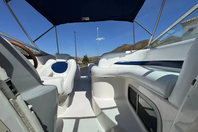 Slide: The Image of 2004 Chaparral Signature 260 boat interior with seating and canopy under clear sky. - 26