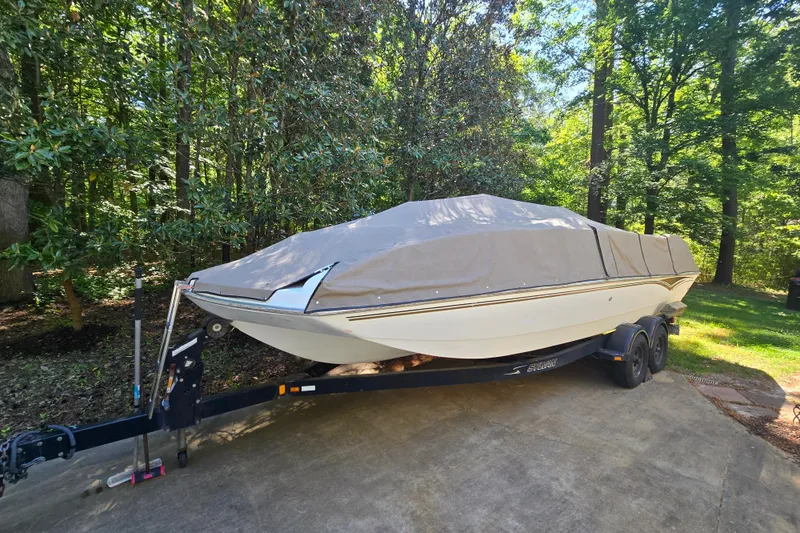 The Image of 2001 Smoker Craft 2310 Commander boat covered on trailer in wooded area. - 1