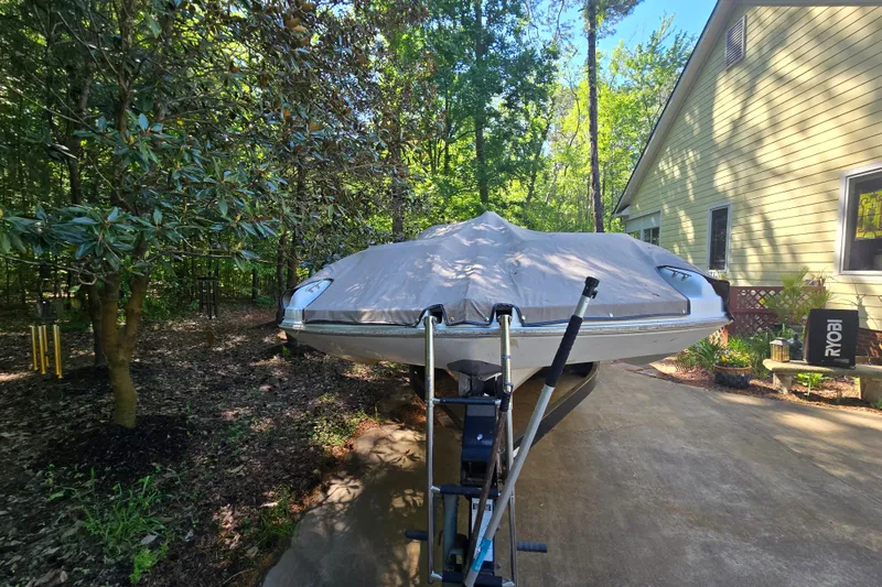 Slide: The Image of Covered 2001 Smoker Craft 2310 Commander boat parked on a driveway beside a house. - 3