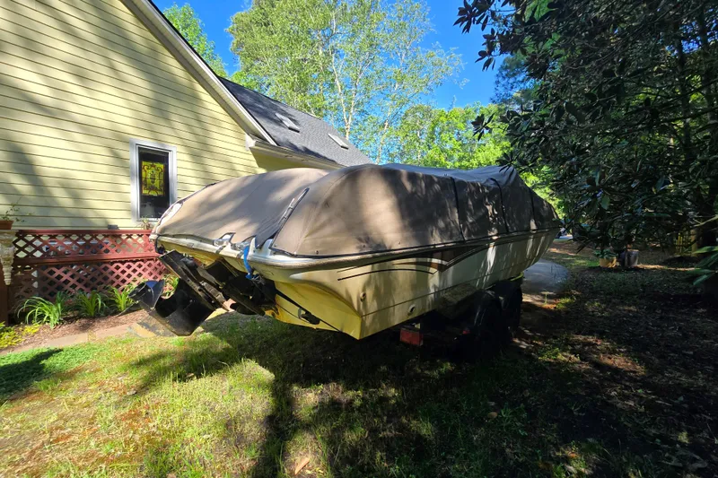 Slide: The Image of Covered 2001 Smoker Craft 2310 Commander boat parked beside a house in a wooded area. - 4
