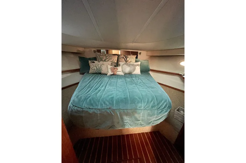 Slide: The Image of Cozy bedroom interior of 2002 Tiara Yachts 4100 Open with teal bedding and decorative pillows. - 5