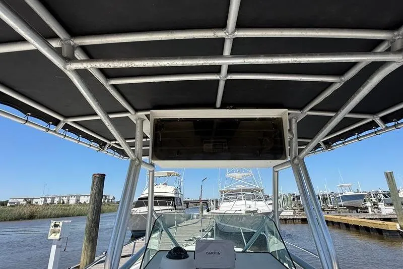 Slide: The Image of 2003 Robalo R230 Center Console boat docked, featuring sturdy T-top and clear blue sky. - 12