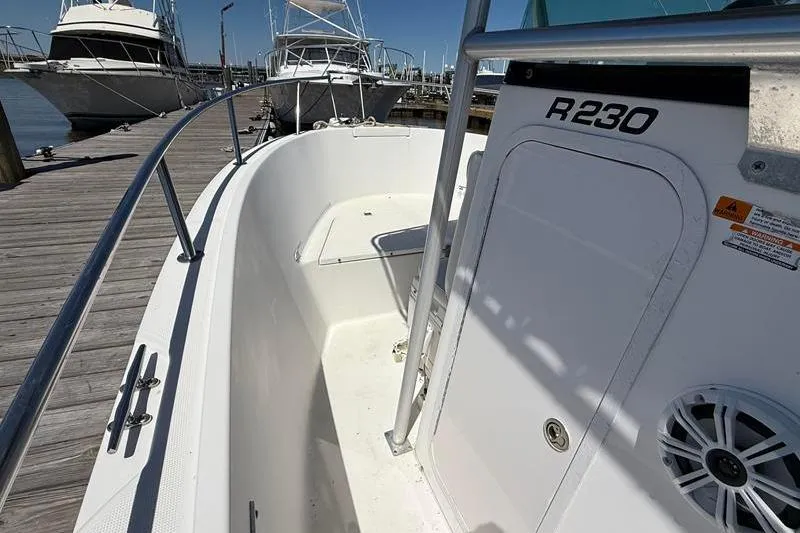 Slide: The Image of 2003 Robalo R230 Center Console boat docked at marina, showcasing interior and railing. - 21