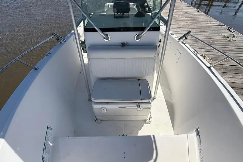 Slide: The Image of 2003 Robalo R230 Center Console boat interior with seating and cooler, docked by the water. - 26