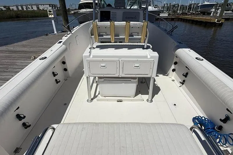 Slide: The Image of 2003 Robalo R230 Center Console boat interior with seating and storage, docked by the water. - 4