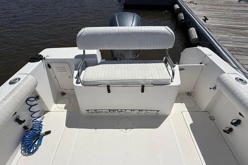 Slide: The Image of 2003 Robalo R230 Center Console boat interior with seating and motor, docked by wooden pier. - 6