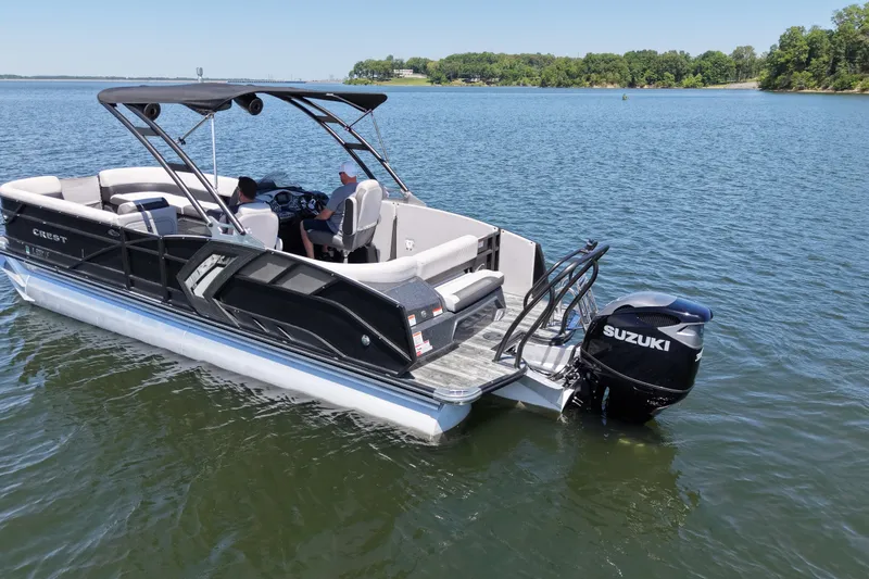 Slide: The Image of 2021 Crest RS250 pontoon boat with Suzuki outboard motor on a serene lake. - 2
