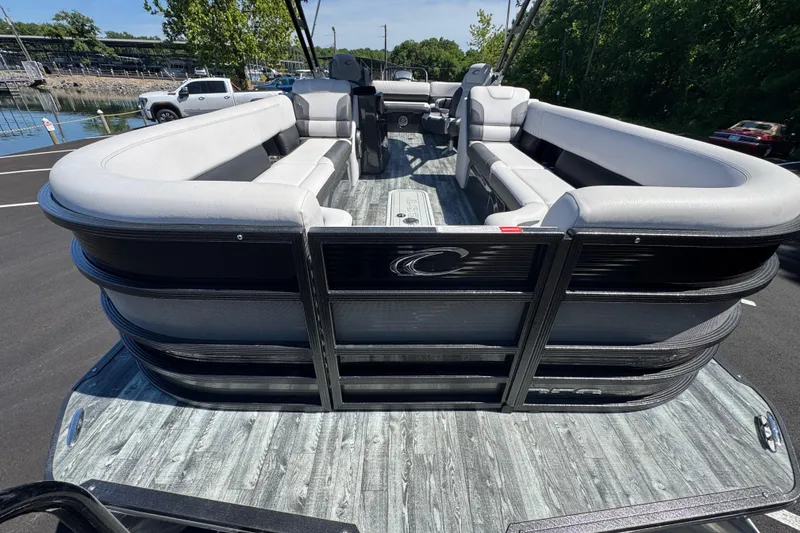 Slide: The Image of 2021 Crest RS250 pontoon boat with spacious seating and sleek design, docked near a marina. - 24