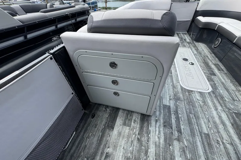 Slide: The Image of 2021 Crest RS250 boat interior with gray seating and storage drawers on wood-patterned flooring. - 36