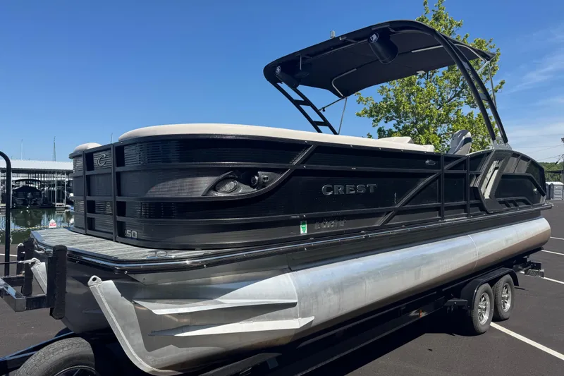 Slide: The Image of 2021 Crest RS250 pontoon boat on trailer, sleek black design, sunny day. - 6