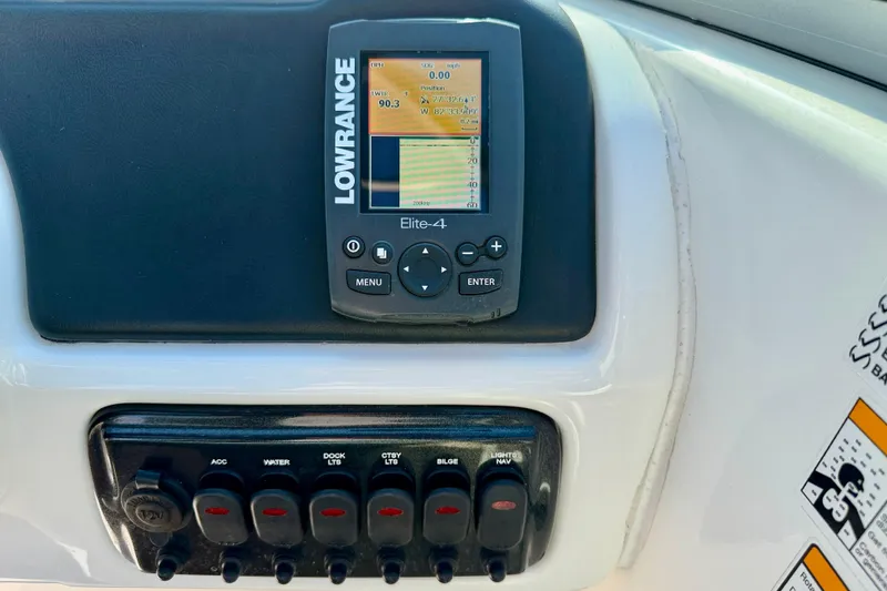 Slide: The Image of Lowrance Elite-4 fishfinder on 2014 NauticStar 243DC Sport Deck dashboard with control switches. - 17