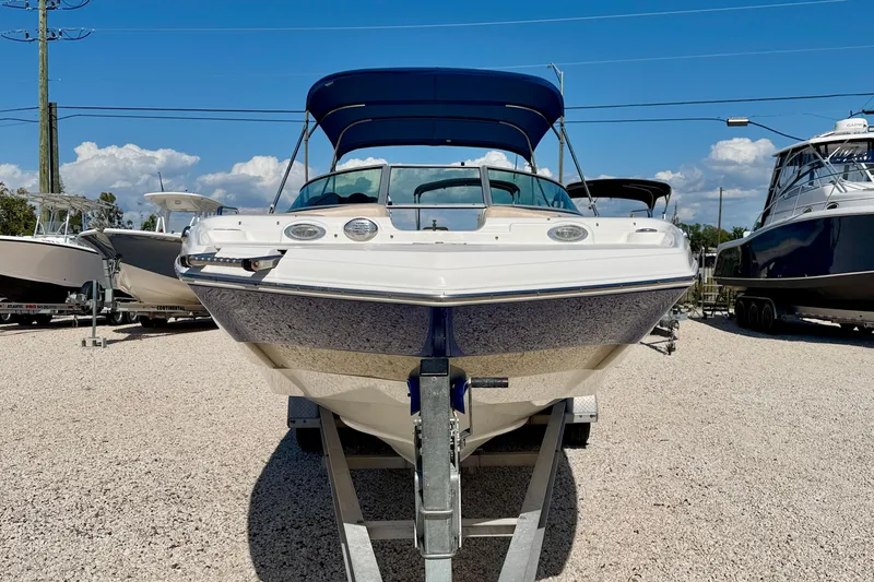 Slide: The Image of 2014 NauticStar 243DC Sport Deck boat on trailer, sunny day, blue canopy. - 2