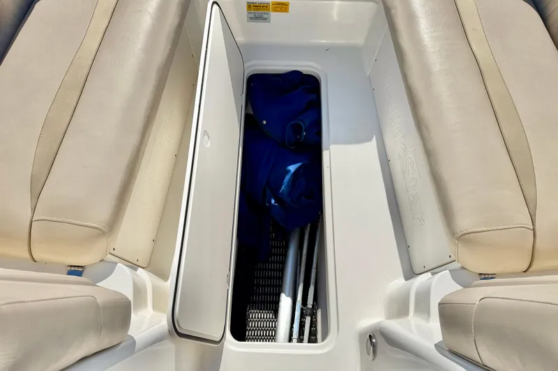 Slide: The Image of 2014 NauticStar 243DC Sport Deck boat storage compartment with beige seating. - 28