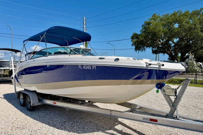 Slide: The Image of 2014 NauticStar 243DC Sport Deck boat on trailer, blue and white, parked outdoors. - 3