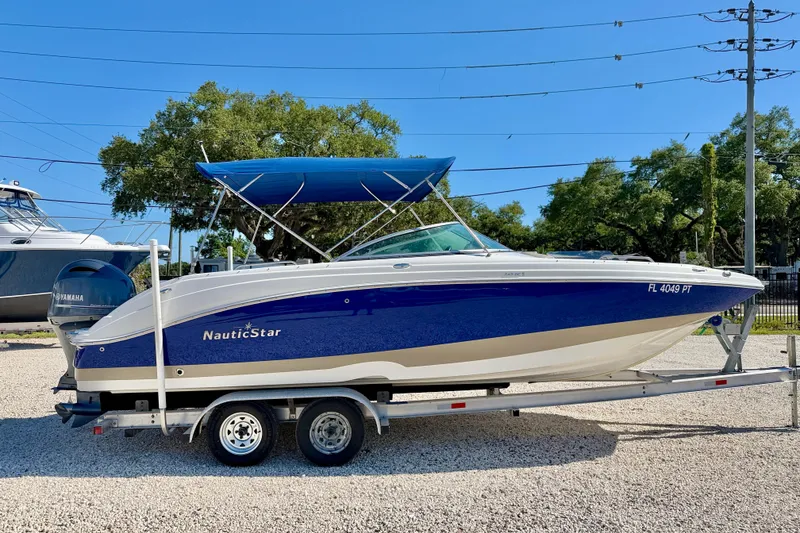 Slide: The Image of 2014 NauticStar 243DC Sport Deck boat on trailer, blue and white design, sunny day. - 4