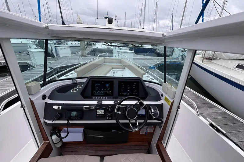 Slide: The Image of Interior view of 2022 Axopar 28 Cabin boat, featuring modern seating and steering wheel. - 13