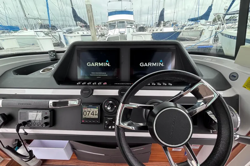 Slide: The Image of 2022 Axopar 28 Cabin boat interior with modern dashboard and steering wheel at marina. - 14
