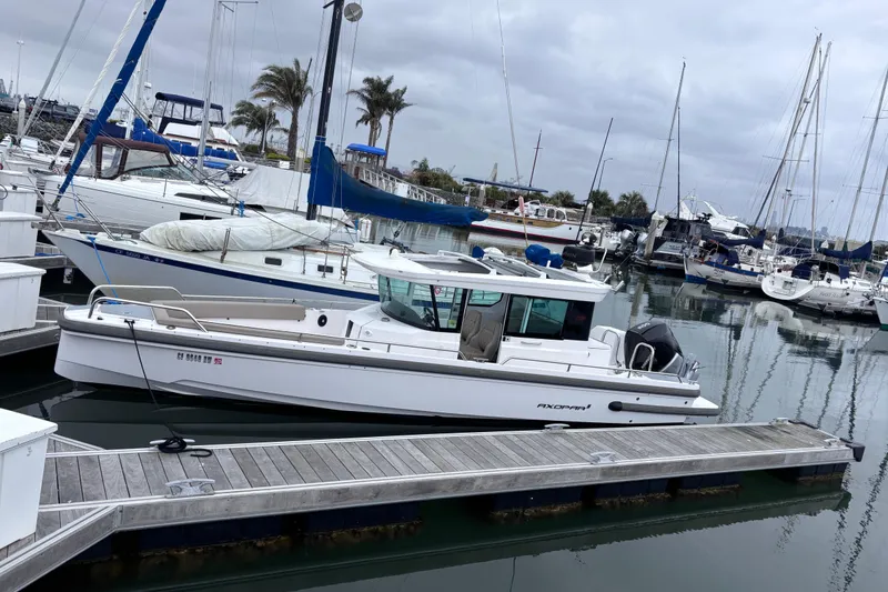 Slide: The Image of 2022 Axopar 28 Cabin boat docked in a marina with sailboats. - 2
