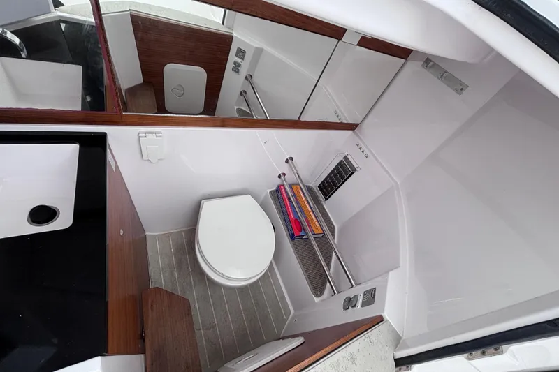 Slide: The Image of Interior view of 2022 Axopar 28 Cabin boat's compact bathroom with toilet and storage. - 22