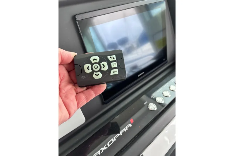 Slide: The Image of 2022 Axopar 28 Cabin boat with radar equipment, docked in a marina under clear blue sky. - 28