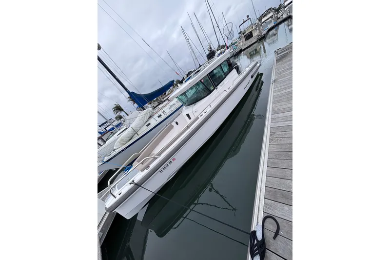 Slide: The Image of 2022 Axopar 28 Cabin boat docked at a marina, surrounded by other vessels. - 3